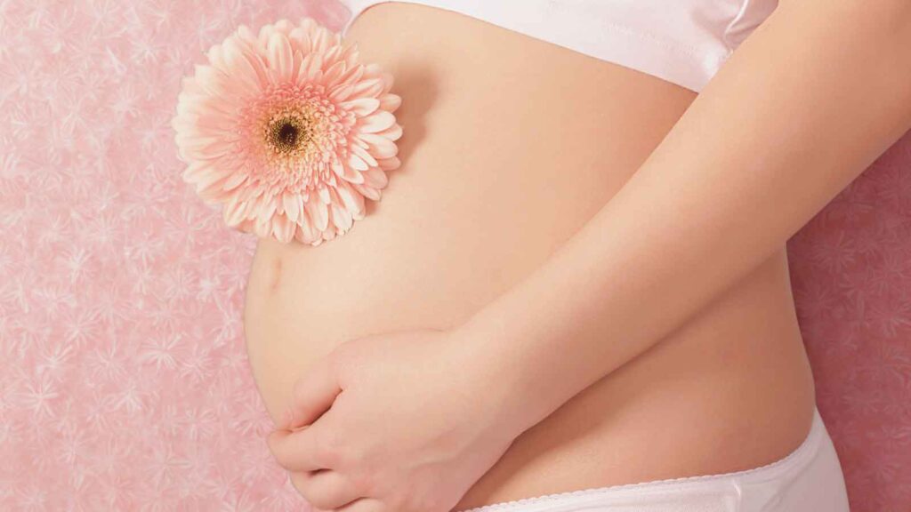 Pregnant woman's belly with pink flower, representing gentle prenatal testing and maternal health care 