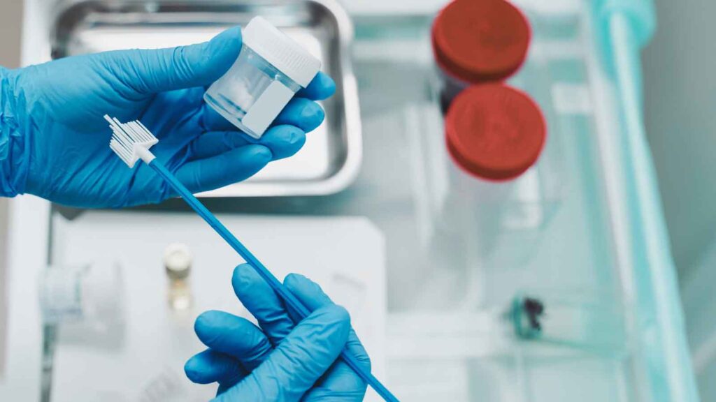 Medical professional preparing Pap smear test specimen in laboratory 
