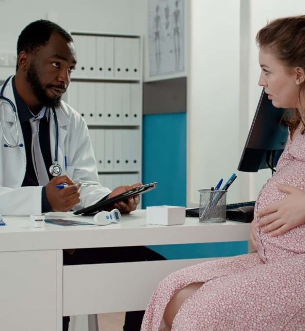 maternity-specialist-taking-notes-digital-tablet-checkup-with-expectant-woman-give-prescription-medicine-male-physician-talking-patient-with-pregnancy-belly-appointment (1)